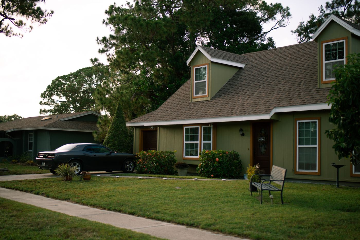 A lived-in family home with a wide front lawn and a car in the driveway