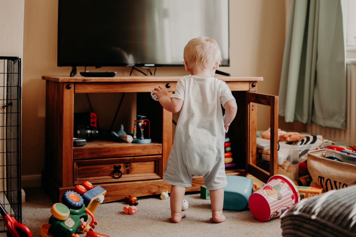 Toddler standing in a living room scattered with toys