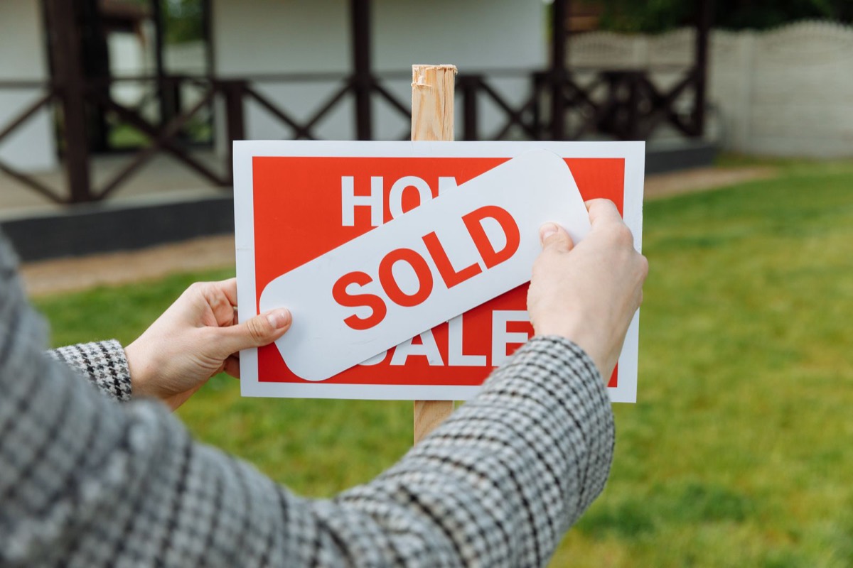 A sold banner going up over the for sale sign in a front yard