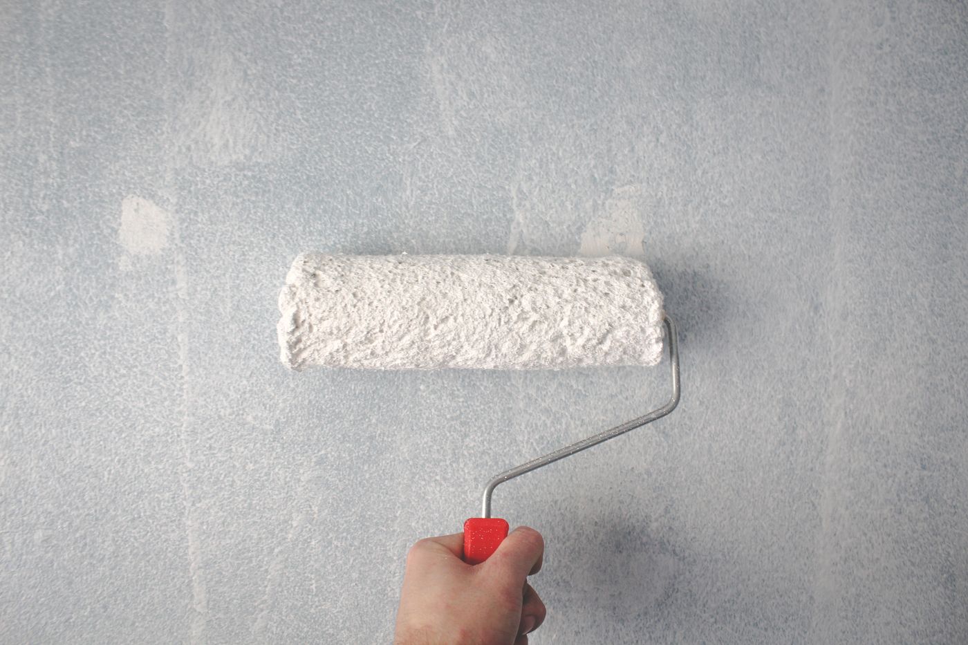 Paint roller putting a fresh coat of white on an interior wall
