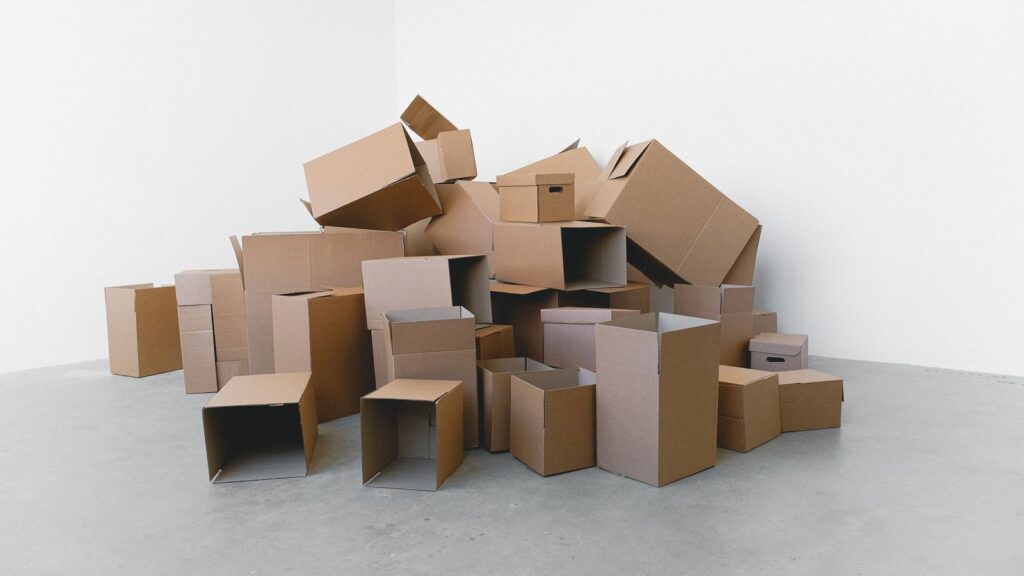 Pile of cardboard containers prepared for relocation on floor at home in daylight on white background