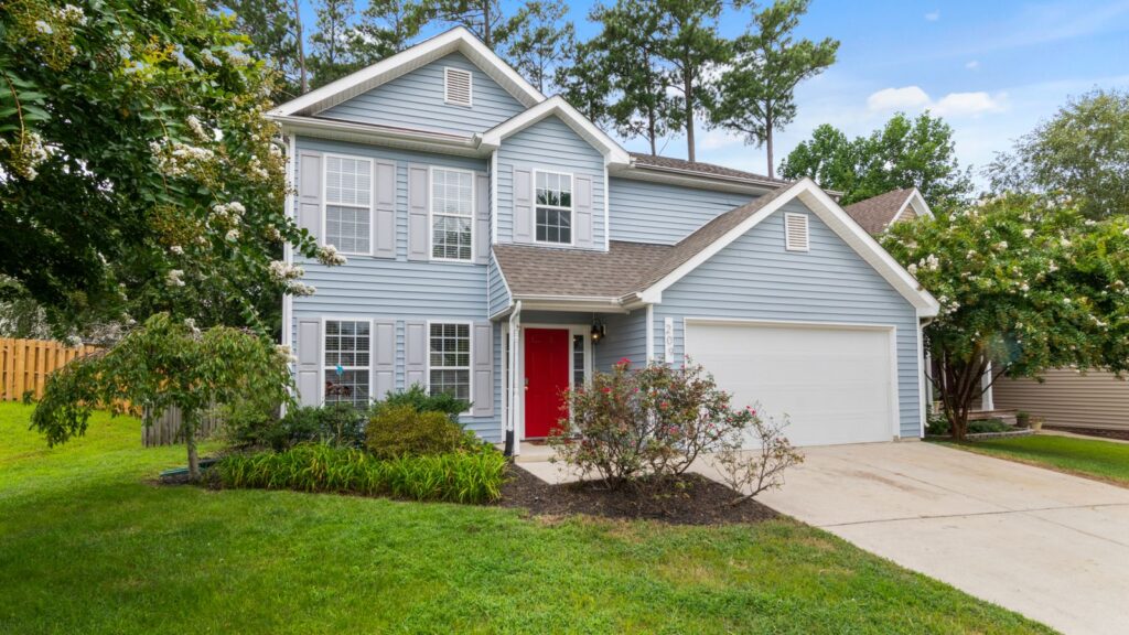 Charming suburban two-story house with a well-maintained lawn and vibrant garden.