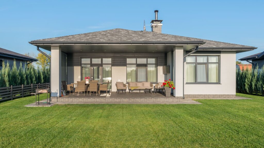 Contemporary house exterior with a large backyard patio and manicured lawn.