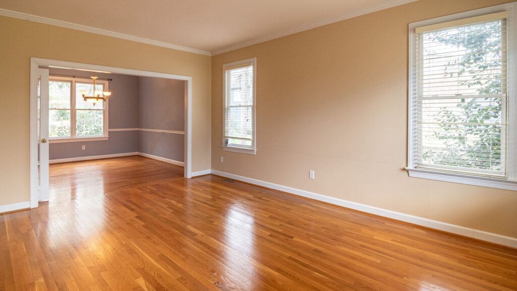 Bright empty room with wooden floors and large windows, ideal for real estate listings.