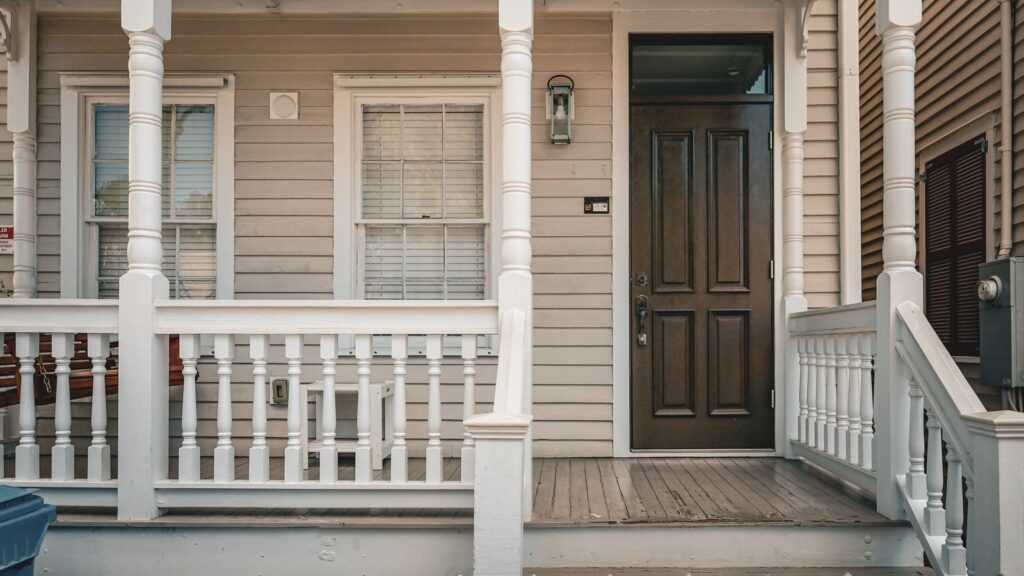 A classic wooden house porch with a decorative entrance and picket fence.